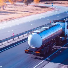 Ein Tankwagen transportiert **Gefahrgut ADR** auf einer Autobahn. Der LKW fährt auf der rechten Spur, die Sonne wirft lange Schatten.