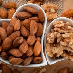 Deux bols en forme de cœur remplis d'amandes et de noix. Une belle présentation de ces oléagineux, parfaits pour une liste d'en-cas sains.