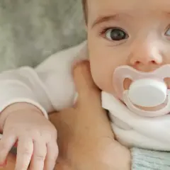 Malutkie dziecko z różowym smoczkiem w buzi. Czas pomyśleć, jak odzwyczaić dziecko od smoczka, by mogło swobodnie się rozwijać.