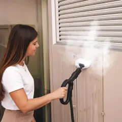 Donna pulisce le tapparelle con un pulitore a vapore, rimuovendo lo sporco in modo efficace.