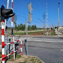 Sygnalizacja świetlna i rogatki na przejeździe kolejowym. Czekam na pociąg, by móc bezpiecznie przejechać.