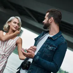 Kobieta w sukience w paski i mężczyzna z aparatem rozmawiają. Może to być wskazówka, co zrobić, by facet cię szanował: bądź sobą i rozwijaj swoje pasje.