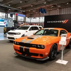 Pomarańczowy Dodge Challenger SRT na wystawie, obok białego Durango. Sprawdź dodge challenger cena i dostępne modele.
