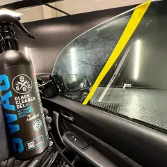 Rękawica z preparatem SWAG Glass Cleaner Gel pokazuje, czym umyć szyby w samochodzie. Żółta taśma na szybie wyznacza obszar czyszczenia.