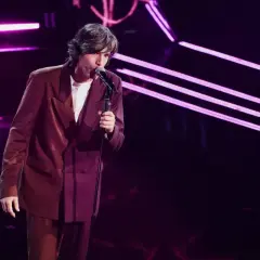 Sara, la cantante, si esibisce sul palco con un completo bordeaux, illuminata da luci viola.