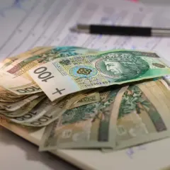 Stos banknotów 100 zł na dokumentach, gotowy na kredyt 50 tys. Długopis leży obok.