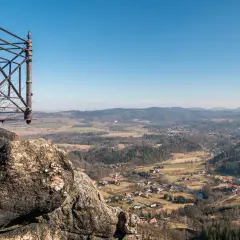 Widok z punktu widokowego na rudawy janowickie szlaki. W dole malownicza dolina z zabudowaniami i lasami.