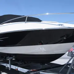 Barca sportiva bianca e nera su carrello, pronta per il varo. I candelieri sono i supporti metallici che la tengono ferma.