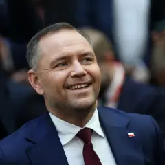 Uśmiechnięty mężczyzna w garniturze z polską flagą na klapie. Czy to jego styl życia wyjaśnia, dlaczego urząd prezydenta jest uznawany za najdroższy w utrzymaniu w całej Europie Środkowej?