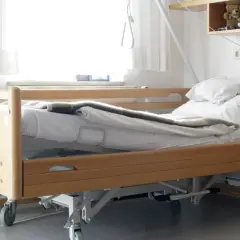 Ein Pflegebett mit Holzrahmen und Rädern, bereit, wenn Sie ein Pflegebett beantragen müssen.