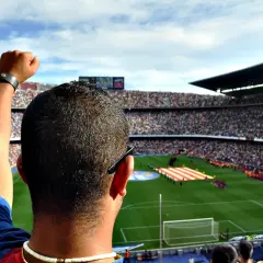 Kibic z podniesioną pięścią na stadionie, dumny jak właściciel Barcelony.