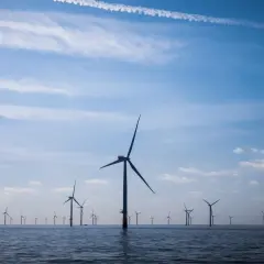 Ogromne farmy wiatrowe na Bałtyku, z wiatrakami na tle błękitnego nieba z chmurami.