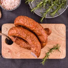 Wędzona kiełbasa na desce z rozmarynem, solą i pieprzem.
