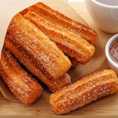 Churros przepis: złociste, posypane cukrem paluszki z ciasta smażonego na głębokim tłuszczu, podane z czekoladą i karmelem.