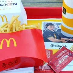 Na tacy McDonald's: duża porcja frytek, burger supreme chicken, napój i ketchup. Zastanawiasz się, ile kosztują duże frytki w maku?