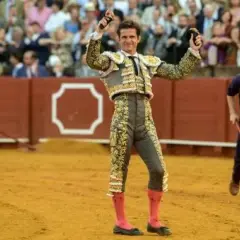 El Juli, torero con traje de luces, levanta las manos en la arena.