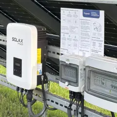 Falownik Solax Power i skrzynki przyłączeniowe na tle paneli PV. Zastanawiasz się, ile kosztuje wymiana falownika? Sprawdź instrukcje i kontakty.