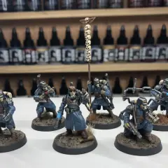 Krieg command squad w niebieskich mundurach, z karabinami i sztandar z czaszkami, gotowi do walki.