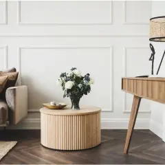 Elegancki salon glamour z dominującym drewnem. Miękka sofa, okrągły stolik i stylowe biurko tworzą przytulną przestrzeń.
