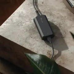 Chargeur noir avec une lumière verte allumée, posé sur une table en pierre. La question "peut on charger une batterie 4ah avec un chargeur 2ah" est soulevée par cet appareil.