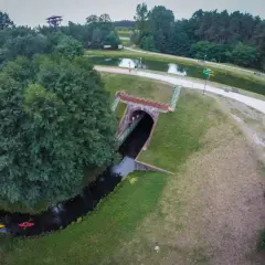 Akwedukt w Fojutowie, gdzie rzeka przepływa pod ziemią, a nad nią rozciąga się malowniczy park z jeziorem i wieżą widokową.