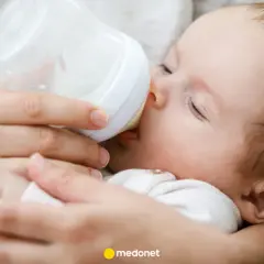 Dziecko pije mleko modyfikowane z butelki. Mama karmi maluszka, który spokojnie zasypia.