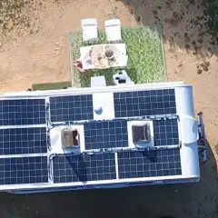 Kamper z panelami słonecznymi na dachu, idealny do życia w stylu instalacja off grid. Na zewnątrz stolik z kawą i krzesła.