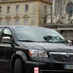 Czarny Lancia Voyager na tle zabytkowej architektury.