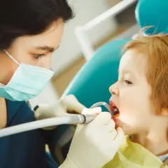 Dentystka bada zęby dziecka, by zapobiec chorobom zębów u dzieci.