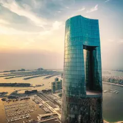 Imponujący, szklany wieżowiec, najwyższy hotel na świecie, góruje nad Dubajem o zachodzie słońca. Widok na sztuczne wyspy w kształcie palmy.