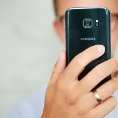 Osoba trzyma czarny telefon Samsung, pokazując tył z aparatem. Dowiedz się, jak poprawić jakość aparatu w telefonie Samsung.