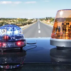 Deux gyrophares sur le toit d'une voiture, sur une route déserte. L'un est bleu et rouge, l'autre orange avec des silhouettes. Indispensable équipement obligatoire voiture Espagne pour la sécurité.