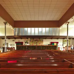 Intérieur d'une église protestante, avec des bancs en bois verni et une fresque colorée au mur. Un lieu paisible pour un baptême chez les protestants.