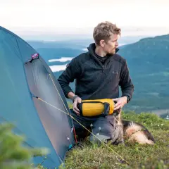 Man med hund förbereder tältet för en vintervandring i fjällen.