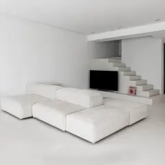 Soggiorno minimalista con divano modulare bianco e pavimento in resina epossidica opaca. Scale moderne conducono a un'area con TV.