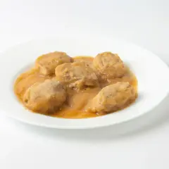 Solomillo de cerdo con manzana en salsa, servido en un plato blanco.