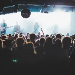 Publik njuter av en konsert i Stockholm idag. Bandet spelar på scenen medan publiken filmar med sina mobiler.