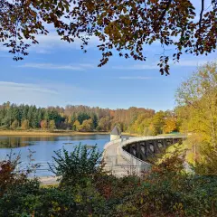 Herbstlicher Spaziergang auf dem panzertalsperre rundweg. Bunte Blätter und ein klarer Himmel über dem Stausee.