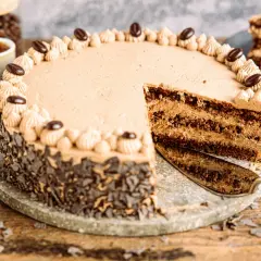 Eine köstliche Kaffee Torte mit Schokoladenraspeln und Kaffeebohnen-Dekoration. Ein Stück wurde bereits angeschnitten.