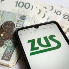 Złotówki i monety na ekranie telefonu z logo ZUS. Sprawdzanie emerytury pomostowej warunki.