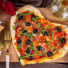 Pizza w kształcie serca z pomidorami, oliwkami i rukolą. Idealna na romantyczną kolację w domu, co ugotować?