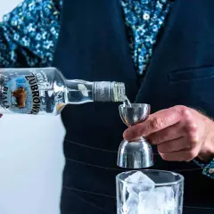Wybierasz jaka wódka na wesele? Żubrówka Biała idealna do drinków, nalewana przez barmana do kieliszka z lodem.