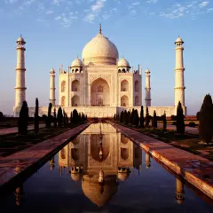 Der Taj Mahal, eine Moschee und ein Mausoleum, spiegelt sich im Wasser.