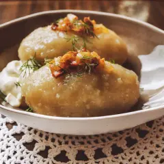 Cepelinai, comida típica de Lituania, servidos con crema agria y tocino crujiente.