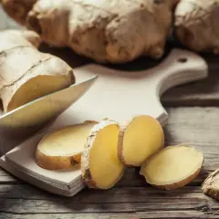 Un cuchillo corta rodajas de jengibre fresco sobre una tabla de cortar. El jengibre es una raíz aromática con muchos usos.