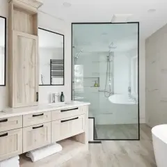 Salle de bain moderne avec double vasque, douche vitrée et baignoire. L'installation plomberie salle de bain est soignée, avec des robinetteries chromées et un sèche-serviettes noir.