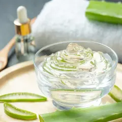 Przezroczysty żel z aloesu, liście aloesu i buteleczka z pipetką. Naturalny **aloe barbadensis leaf extract** do pielęgnacji.