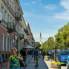 Spacerem ulicą w Częstochowie, w oddali widać wieżę Jasnej Góry. Trasa pielgrzymkowa tętni życiem.