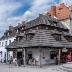 Urokliwe zabytki w Polsce: kamienice o drewnianych dachach i brukowana uliczka z turystami.