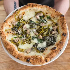 Pizza mit Salsiccia und Friarielli, belegt mit geschmolzenem Käse und geriebenem Parmesan.